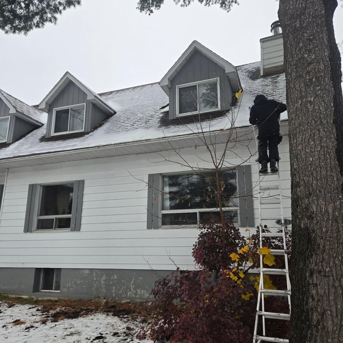 Technicien sur une échelle nettoyant les gouttières d'une maison à Laval